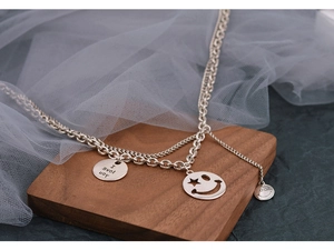 Detail of layered silver chain necklace with smile face charms and I love you pendant