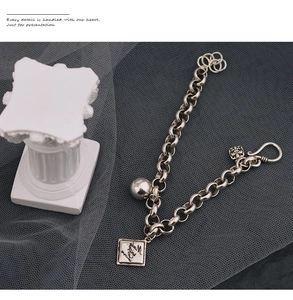 Detailansicht eines Retro-Silberkettenarmbands mit Kugel, Quadrat und Kreuzanhängern