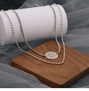 Close-up of double-layer chain necklace with MORE YOU LOVE engraved round pendant