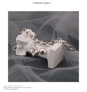 Detail eines Gliederketten-Armbands aus Silber mit graviertem quadratischem Anhänger und Perle