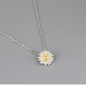 Close-up of daisy pendant necklace with silver petals and a golden center core
