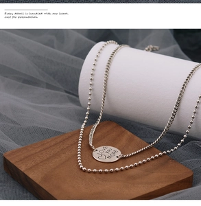 Detail of double-layer silver necklace with Love You More engraved round pendant