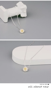 Detail view of dainty daisy pendant necklace featuring white petals and yellow flower center