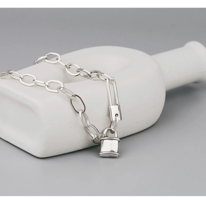 Gros plan du pendentif cadenas argenté et du fermoir épingle sur le collier à chaîne
