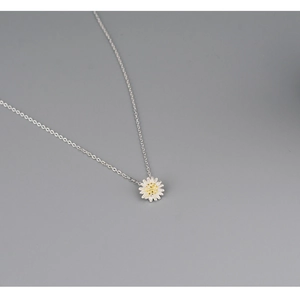 Detail of silver daisy flower pendant with white petals and yellow center on fine chain