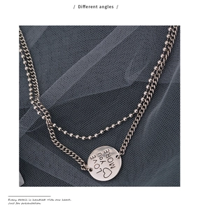 Detail of silver double-layered necklace with round LOVE YOU MORE engraved pendant