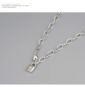 Gros plan d'un pendentif cadenas en argent sur une chaîne à maillons ovales