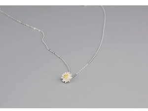 Macro shot of silver daisy pendant with yellow center on fine silver necklace chain