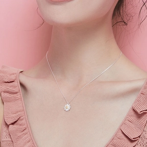 Minimalist daisy pendant necklace with white petals on silver chain worn by model