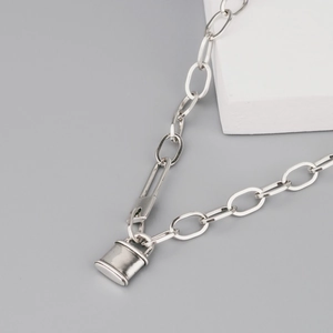 Collier argenté avec pendentif cadenas et fermoir épingle sur surface grise épurée
