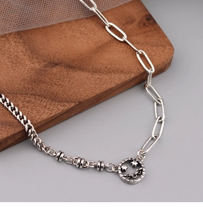 Detail of silver hollow smiley pendant necklace with asymmetric Cuban chain links