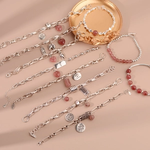 Vintage strawberry quartz bracelets with silver charms and pearls on a decorative tray