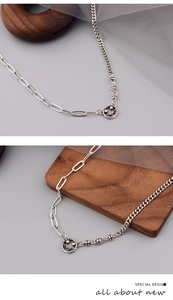 Detail showing asymmetric silver chain with a hollow star-eyed smiley face pendant