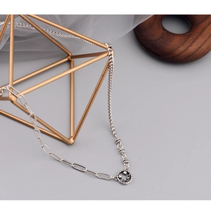 Detail of asymmetric chain necklace with retro hollow star-eye smiley face pendant