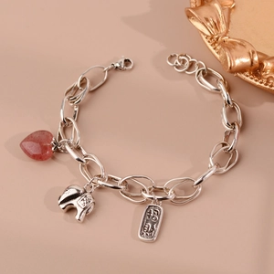 Detailed shot of silver bracelet with heart strawberry quartz and elephant charm
