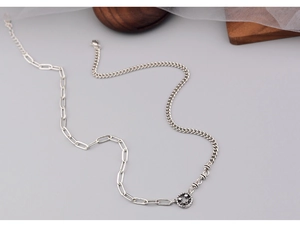 Close-up of asymmetric silver smile pendant necklace with star eyes and mixed chain links