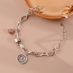 Detail of silver S925 chain bracelet featuring a Roman numeral coin and red stone bead