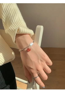 Detail of silver chain bracelet with red heart pendant and LOVE U tag on wrist