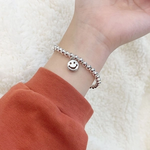 Minimalistisches silbernes Perlenarmband mit Smiley-Anhänger am Handgelenk
