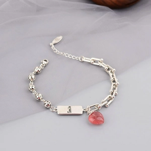 Close-up of strawberry crystal charm and silver Smile plate on the chain bracelet