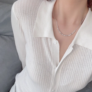 Detailed view of silver irregular cube pendant necklace on a model wearing knitwear