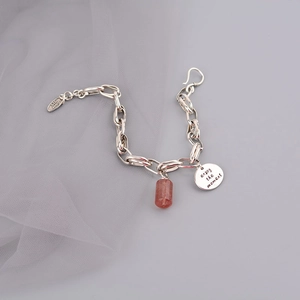Macro shot of vintage silver bracelet with strawberry quartz and engraved charm