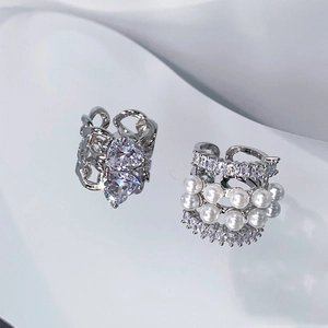 Macro detail of heart zircon ear clip and layered pearl cuff on white texture