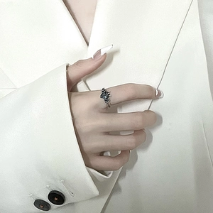 Gothic bat-shaped silver ring with dark gemstone on hand over minimalist background