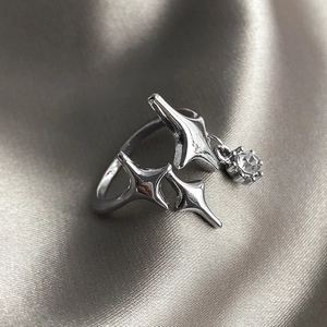 Detail of 925 sterling silver open ring with star pattern and dangling zircon stone