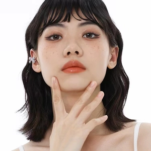 Detailed close-up of a silver bow ear cuff with pink zircons worn on a model's ear