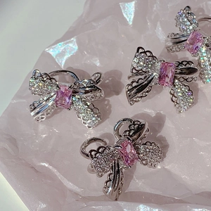Elegant bow-shaped silver ear clips with pink zircon stones on pink crystal rocks