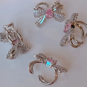 Detailed views of pink zircon bow ear cuffs with silver plating and micro-set crystals