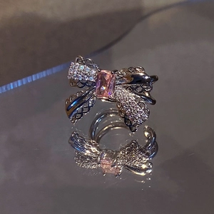 Macro shot of silver bow earring with pink zircon and micro-pave diamond detail