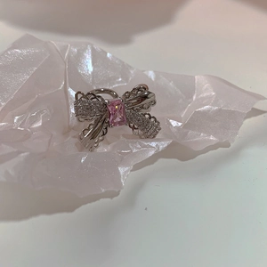 Detailed view of silver bow ear cuff featuring pink zircon and intricate hollow metalwork