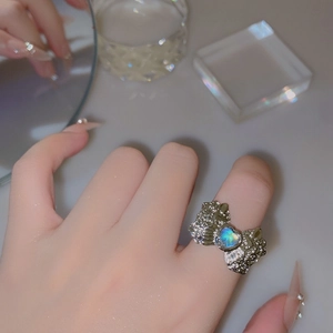 Detailed close-up of a bow-shaped moonstone heart ring with irregular silver texture