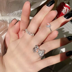 Detailed view of silver bow ring with moonstone and heart-shaped band on hand