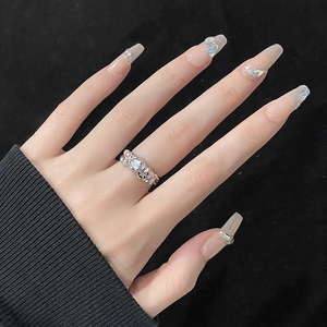 Close-up of irregular silver ring with opal stone worn on finger against black background