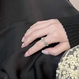 Detail of irregular silver ring with opal stone worn against black fabric background