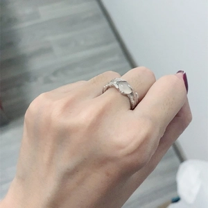 Detailed view of an irregular silver lava ring with an oval opal gemstone on a hand