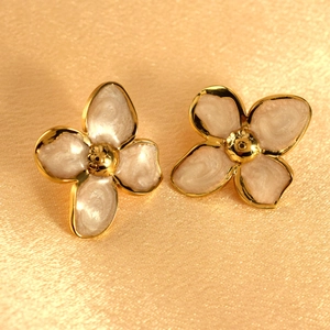 Detail view of four-petal flower stud earrings with white enamel and golden contours