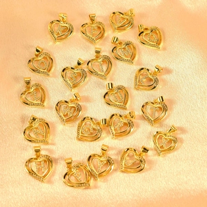 Close-up of gold-plated heart letter pendants with cubic zirconia on champagne silk