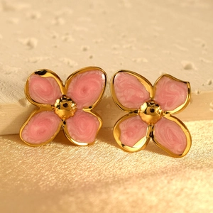 Macro view of pink marble enamel four-petal flower earrings with a golden metal finish