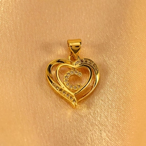 Detailed close-up of golden heart pendant with letter C and sparkling zircon stones