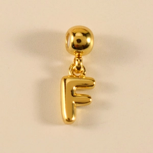 Detailansicht eines polierten goldenen Metallanhängers Buchstabe F mit Kugelverschluss