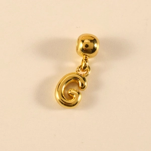 Nahaufnahme des goldenen Buchstaben-G-Anhängers mit Kugelöse auf strukturiertem Grund
