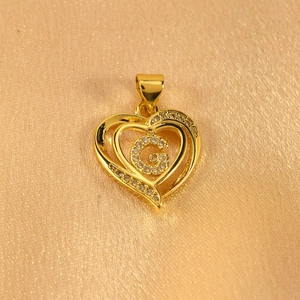Detailed macro view of heart-shaped gold pendant with sparkling pavé letter G design