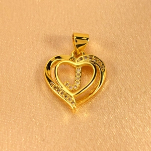 Detail of gold heart pendant with letter J encrusted in brilliant cubic zirconia stones