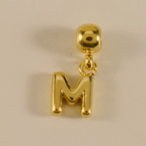 Detailaufnahme von goldenem M-Buchstaben-Anhänger mit polierter Oberfläche
