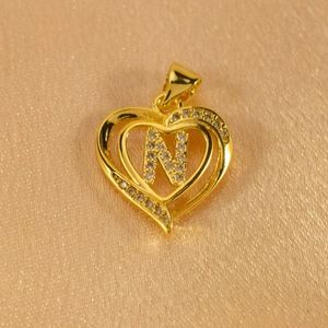 Macro shot of gold-plated heart pendant featuring letter N and sparkling zircon accents