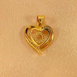 Macro shot of gold heart pendant with crystal accents on a silk champagne fabric